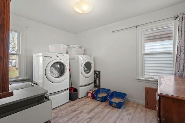 washroom with washing machine and clothes dryer and light hardwood / wood-style flooring