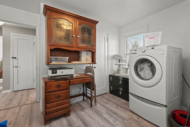 clothes washing area with washer / dryer and light hardwood / wood-style flooring