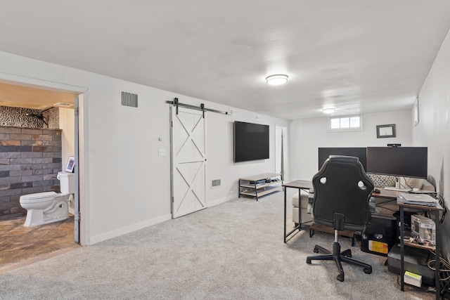 carpeted home office featuring a barn door