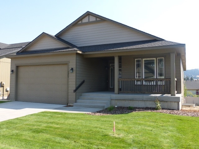 view of front of property featuring a porch, a garage, and a front yard