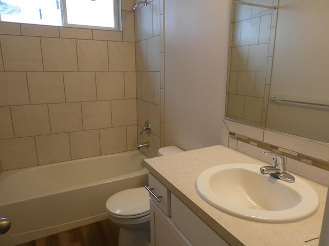 full bathroom with backsplash, tiled shower / bath combo, hardwood / wood-style floors, vanity, and toilet