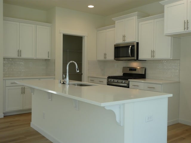 kitchen featuring stainless steel appliances, sink, a center island with sink, and white cabinets