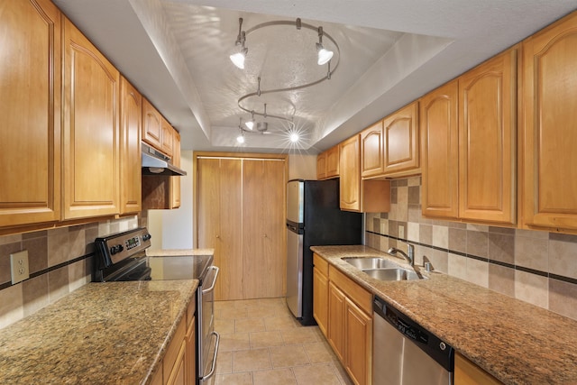 kitchen featuring sink, appliances with stainless steel finishes, light stone counters, tasteful backsplash, and a raised ceiling