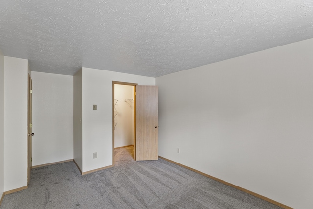 unfurnished bedroom with a walk in closet, light colored carpet, a closet, and a textured ceiling