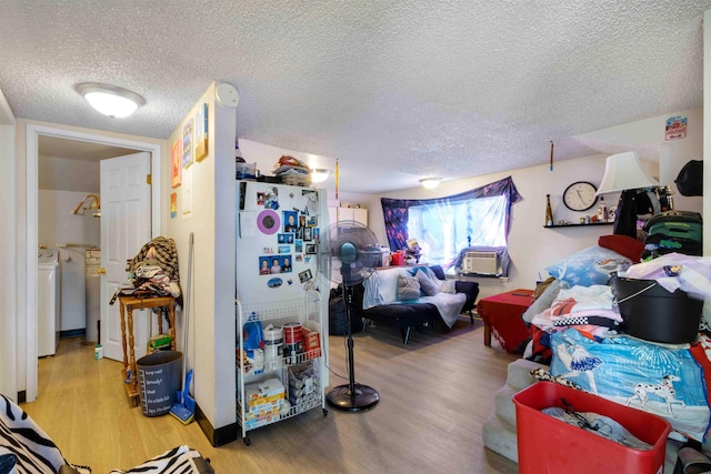 living room with cooling unit, independent washer and dryer, hardwood / wood-style floors, and a textured ceiling