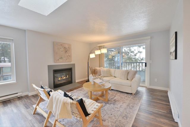 living room featuring a skylight, a textured ceiling, a baseboard radiator, and wood-type flooring