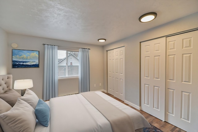 bedroom featuring multiple closets, wood-type flooring, and a textured ceiling