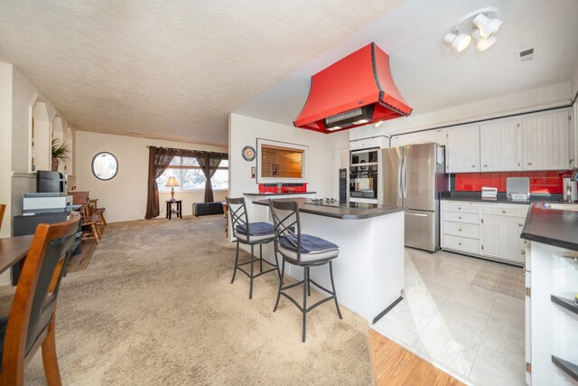 3732 E Westwood Ave, Chattaroy, WA 99003 - kitchen featuring freestanding refrigerator, dark countertops, white cabinets, visible vents, and custom range hood