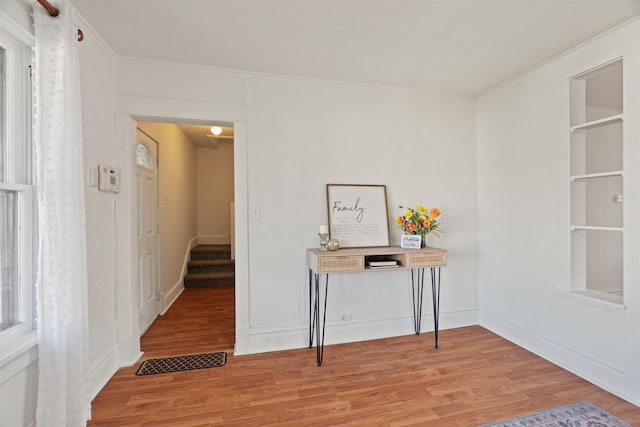 hall with crown molding and light wood-type flooring