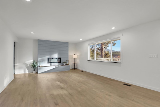 unfurnished living room with a fireplace and light wood-type flooring