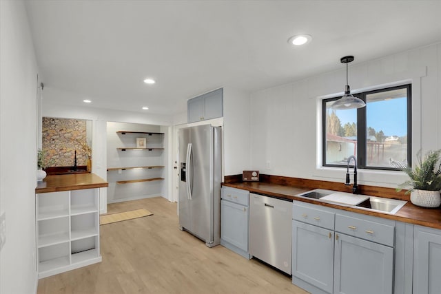 kitchen featuring pendant lighting, sink, wooden counters, stainless steel appliances, and light hardwood / wood-style flooring