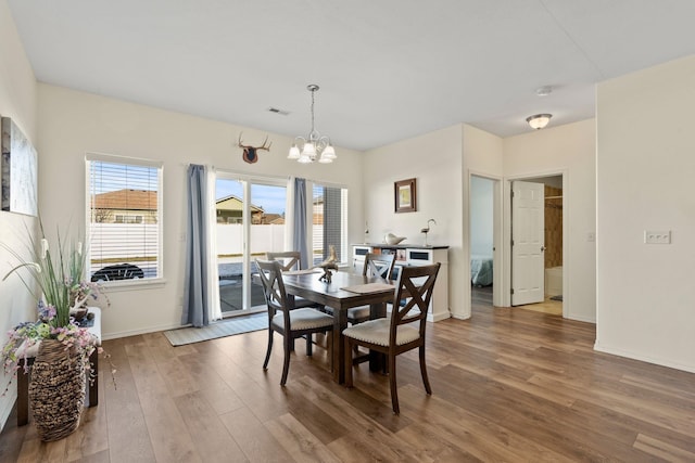 dining space featuring hardwood / wood-style floors, a wealth of natural light, and a chandelier