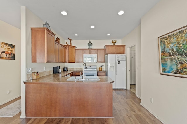 kitchen featuring sink, white appliances, kitchen peninsula, and light wood-type flooring