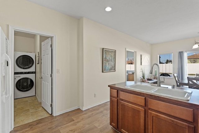 kitchen featuring pendant lighting, stacked washer and dryer, sink, and light hardwood / wood-style flooring