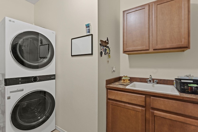 clothes washing area with stacked washer / drying machine, cabinets, and sink