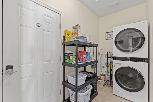 laundry area with stacked washer / drying machine and light tile patterned floors