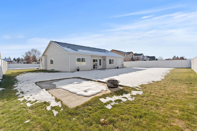 back of house with a fire pit and a lawn