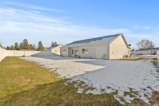 rear view of property with a garage and a yard