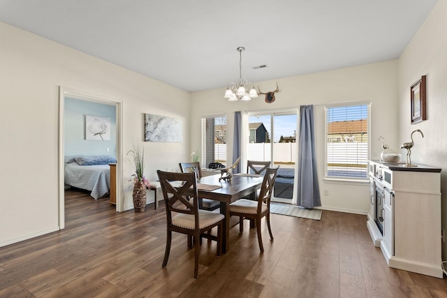 dining space featuring a healthy amount of sunlight, dark hardwood / wood-style floors, and a chandelier