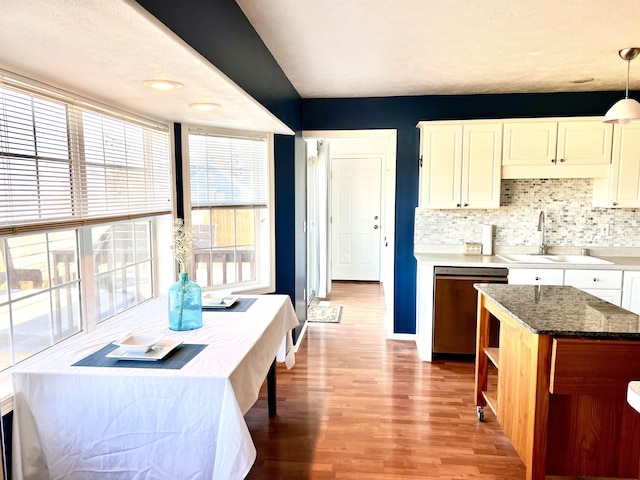 kitchen featuring sink, hanging light fixtures, dishwashing machine, light hardwood / wood-style floors, and decorative backsplash