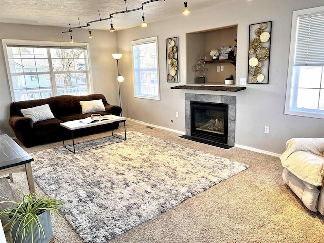 living room with a healthy amount of sunlight, a tiled fireplace, and carpet floors