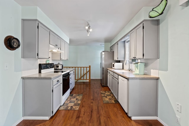 kitchen featuring gray cabinets, rail lighting, sink, dark wood-type flooring, and white appliances