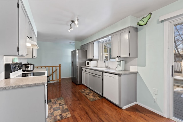 kitchen with dark hardwood / wood-style flooring, sink, white appliances, and plenty of natural light