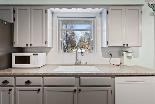 kitchen with sink, white appliances, and backsplash