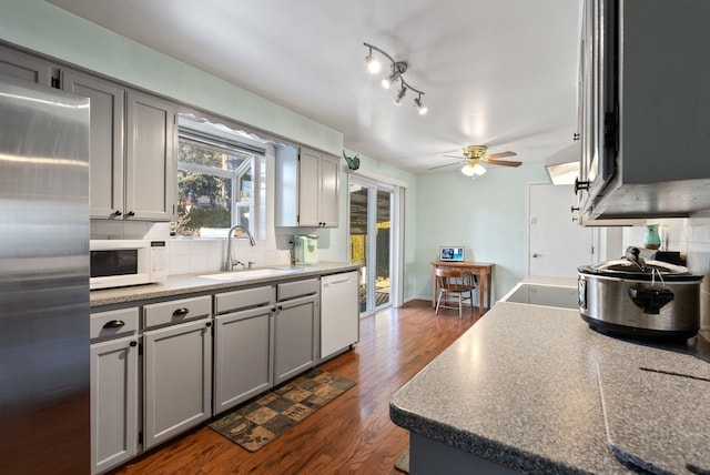 kitchen featuring sink, white appliances, gray cabinets, dark hardwood / wood-style flooring, and decorative backsplash