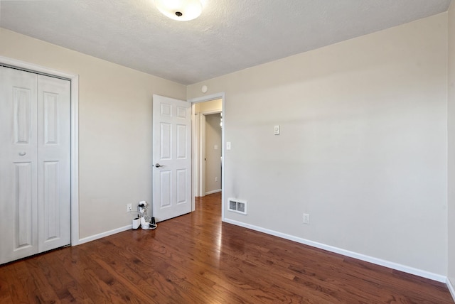 unfurnished bedroom featuring dark hardwood / wood-style flooring, a closet, and a textured ceiling