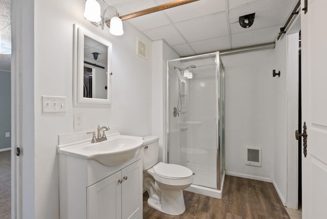 bathroom with walk in shower, toilet, wood-type flooring, vanity, and a drop ceiling