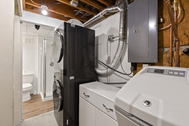 clothes washing area with cabinets, stacked washer / drying machine, and electric panel