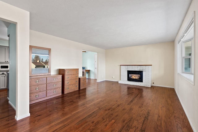 living room with a brick fireplace, a wealth of natural light, a textured ceiling, and dark hardwood / wood-style flooring