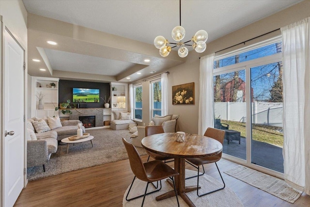 dining area featuring hardwood / wood-style flooring, a raised ceiling, a notable chandelier, and built in shelves