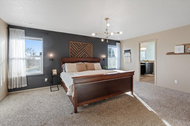 bedroom featuring a chandelier, light colored carpet, and a textured ceiling