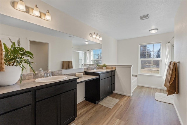 bathroom with vanity, hardwood / wood-style floors, a textured ceiling, and a bathtub