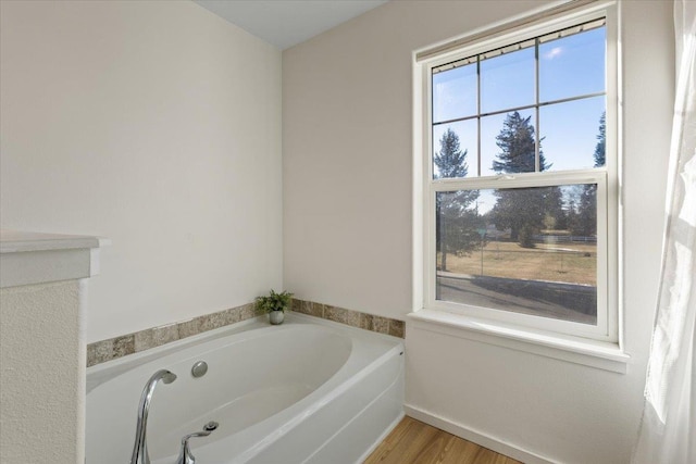 bathroom with a tub to relax in and wood-type flooring