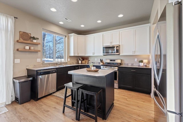 kitchen featuring white cabinetry, sink, a breakfast bar area, a center island, and stainless steel appliances