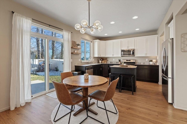 dining space with sink, a chandelier, a textured ceiling, and light hardwood / wood-style floors