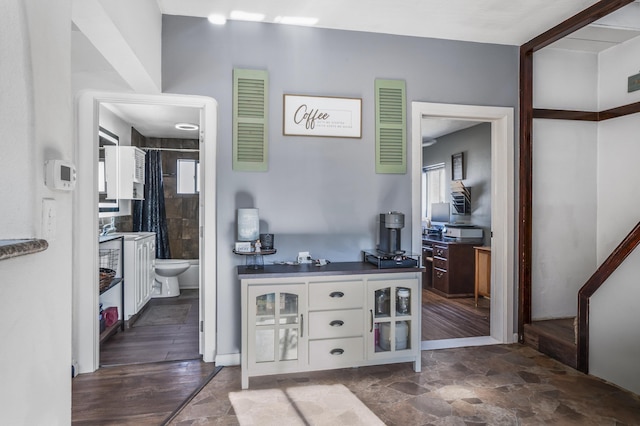 bar with white cabinetry and a healthy amount of sunlight