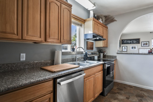 kitchen with rail lighting, appliances with stainless steel finishes, sink, and dark stone counters