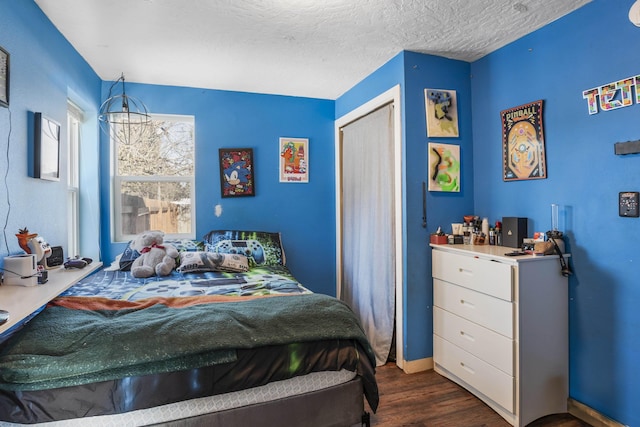 bedroom with dark wood-type flooring, a textured ceiling, and a closet