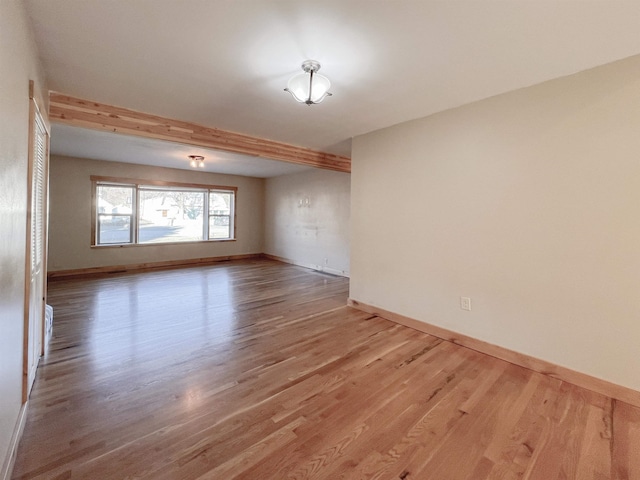 spare room with hardwood / wood-style floors and beam ceiling