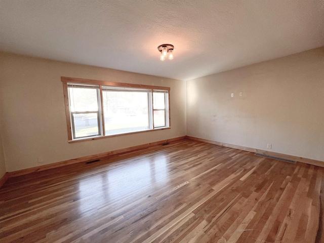 empty room with hardwood / wood-style flooring and a textured ceiling