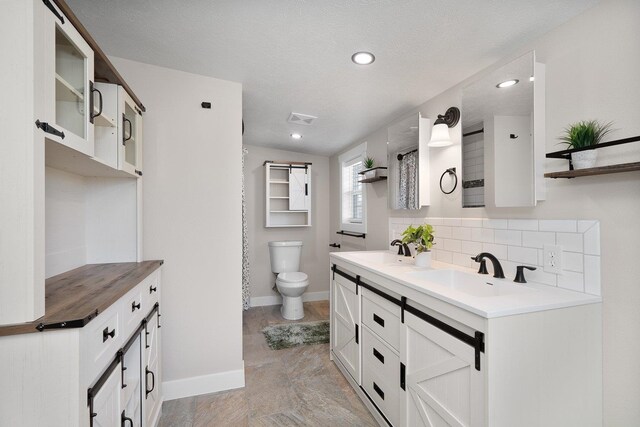 bathroom featuring vanity, toilet, and decorative backsplash