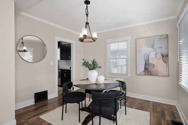 dining room with dark hardwood / wood-style flooring, ornamental molding, a healthy amount of sunlight, and an inviting chandelier