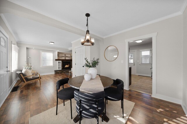 dining space featuring dark wood-type flooring, ornamental molding, and a notable chandelier