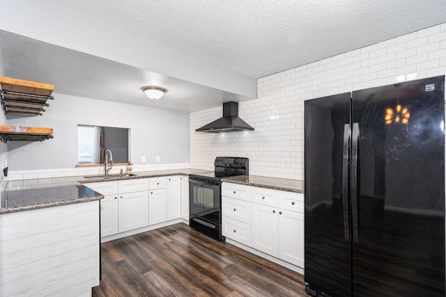 kitchen featuring sink, black appliances, dark stone counters, wall chimney range hood, and white cabinets