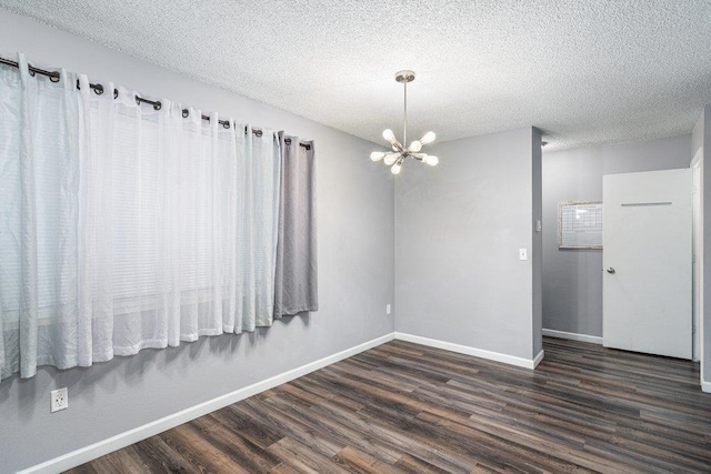 unfurnished room featuring dark hardwood / wood-style floors, a textured ceiling, and an inviting chandelier