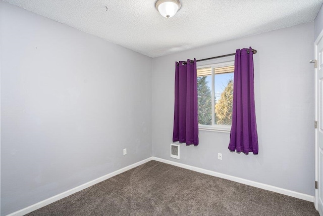 empty room with carpet floors and a textured ceiling